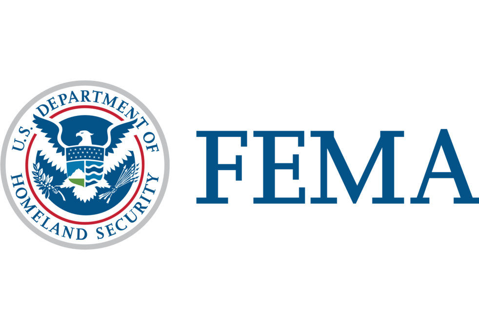 The image shows the FEMA logo. On the left, a circular emblem with an eagle, a shield with various symbols, and "U.S. Department of Homeland Security" written around the outer edge is present. To the right, the acronym "FEMA" is displayed in large, blue capital letters. This news is particularly relevant for residents of Flagler County and Palm Coast.