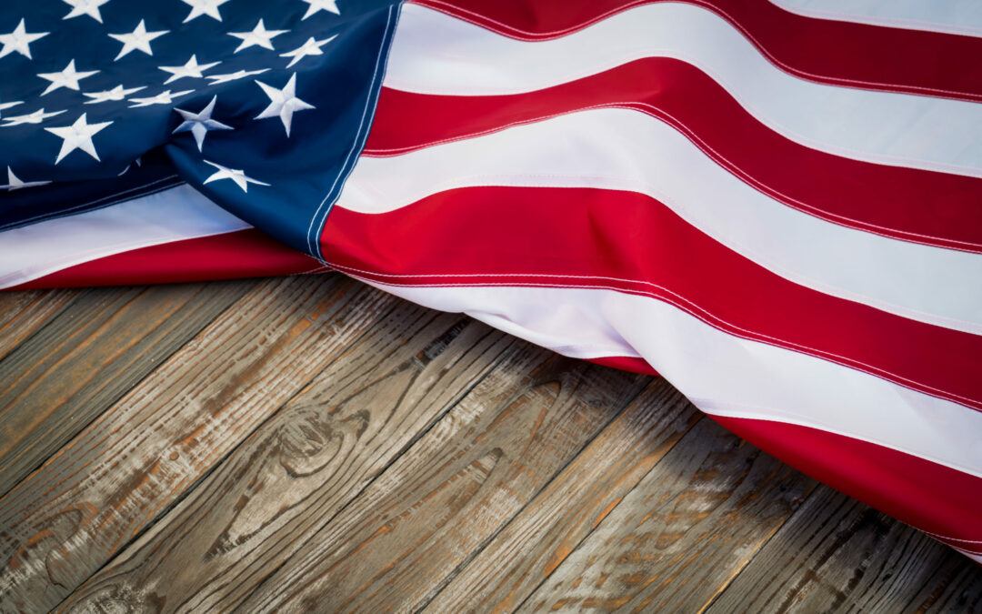 A close-up view of an American flag featuring the stars and stripes, draped over a rustic wooden surface in Flagler County. The flag's red, white, and blue colors contrast vividly with the weathered texture of the wood, capturing a slice of Palm Coast history.