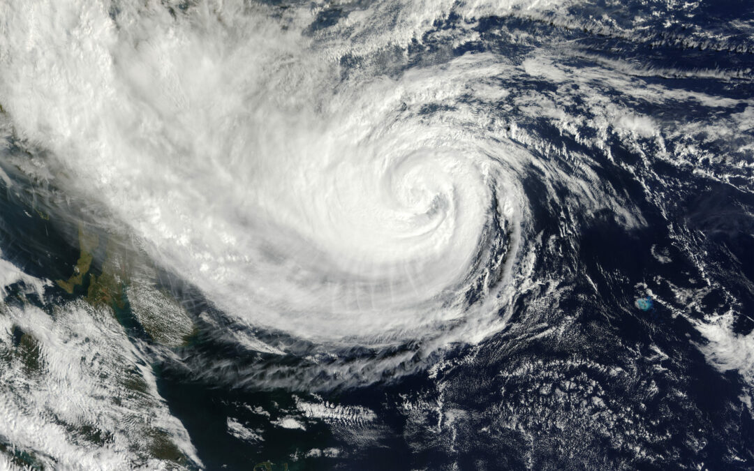 A satellite image of a massive, swirling hurricane over the ocean captures the eye of the storm at its center, surrounded by thick white clouds spiraling outward. With counterclockwise rotation, the dark and turbulent ocean below appears ominous. This significant weather event is now impacting Flagler County and Palm Coast.