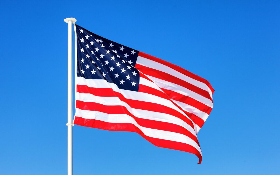 american flag waving blue sky scaled