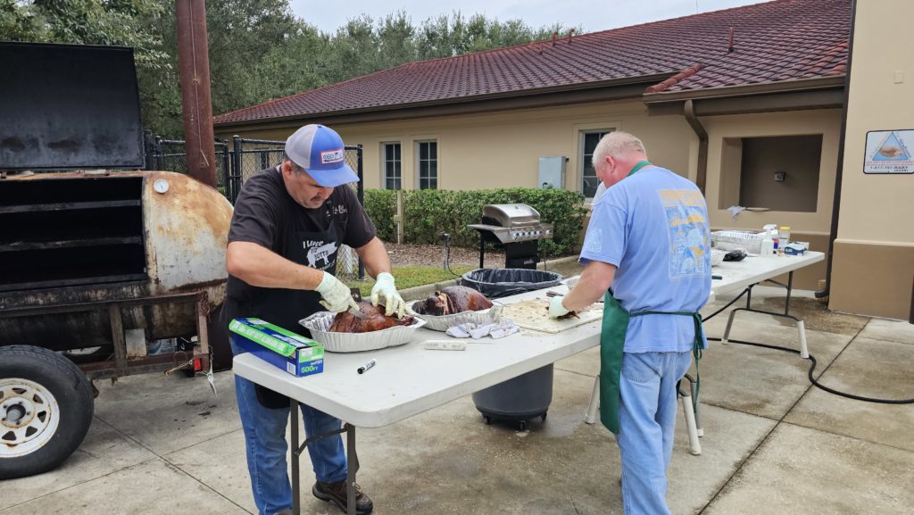 two men cutting up turkeys on a table