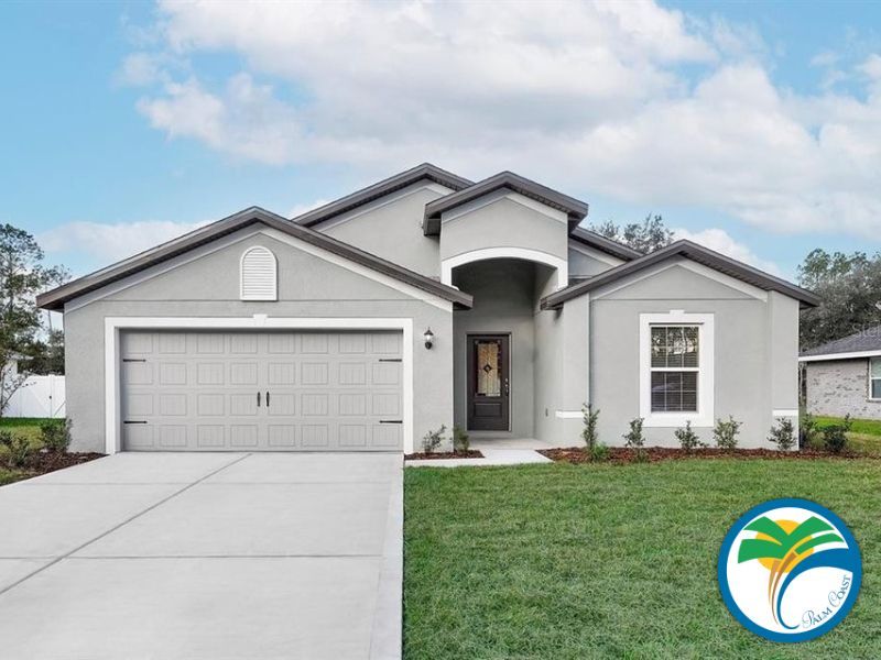 A modern, single story gray house with a well kept lawn and driveway leading to a two car garage The front door features a small, covered porch There is a logo in the bottom right corner with a palm tree and blue waves