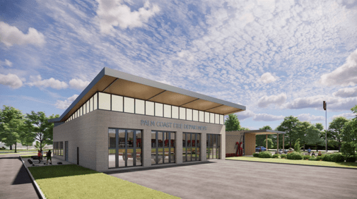 A modern fire station building with large glass windows and a flat roof The sign reads "Palm Coast Fire Department " Surrounding the building are green trees and a partly cloudy sky