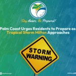 Rainy background with text: "Stay Aware, Be Prepared! Palm Coast Urges Residents to Prepare as Tropical Storm Milton Approaches " A yellow road sign reads "Storm Warning " Social media icons and website link at the bottom