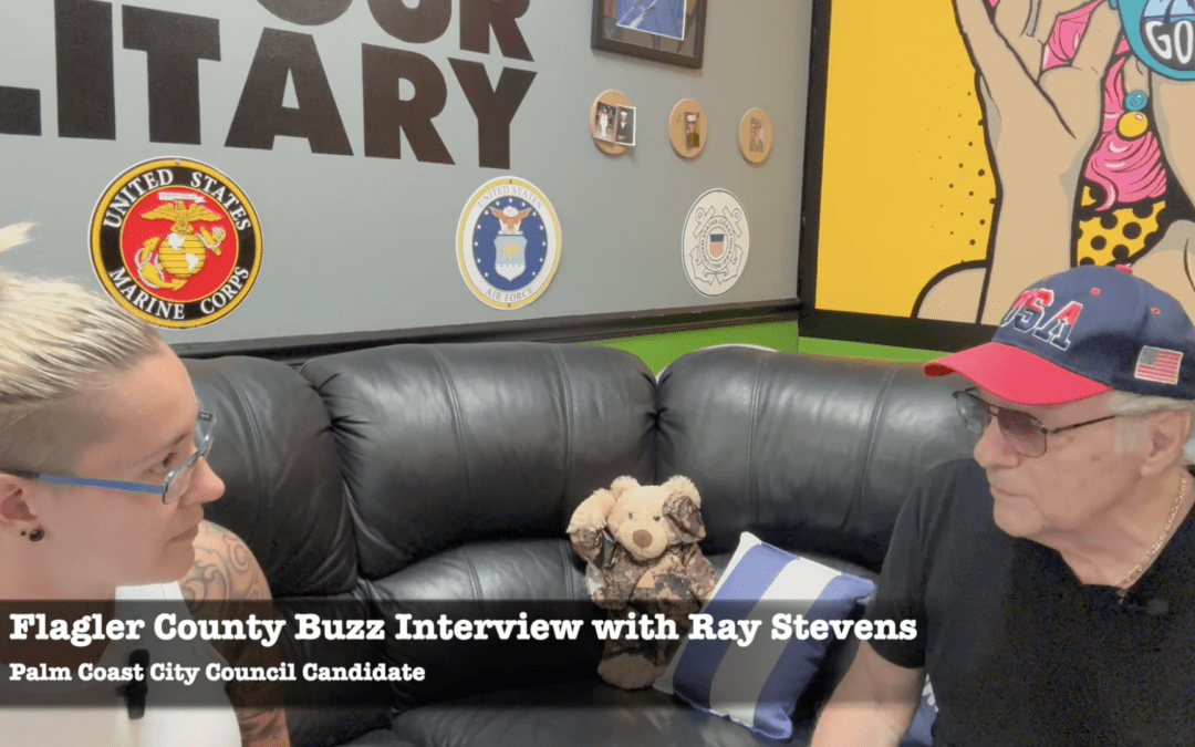 A man and woman sit on a black sofa with a stuffed animal between them in Palm Coast Wall decor includes seals and art Text reads: "Flagler County Buzz Interview with Ray Stevens, Palm Coast City Council Candidate