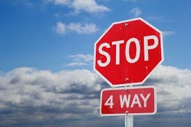 A red stop sign with the words " WAY" beneath it stands against a backdrop of a cloudy blue sky