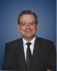 A man in a suit and tie is smiling against a blue background