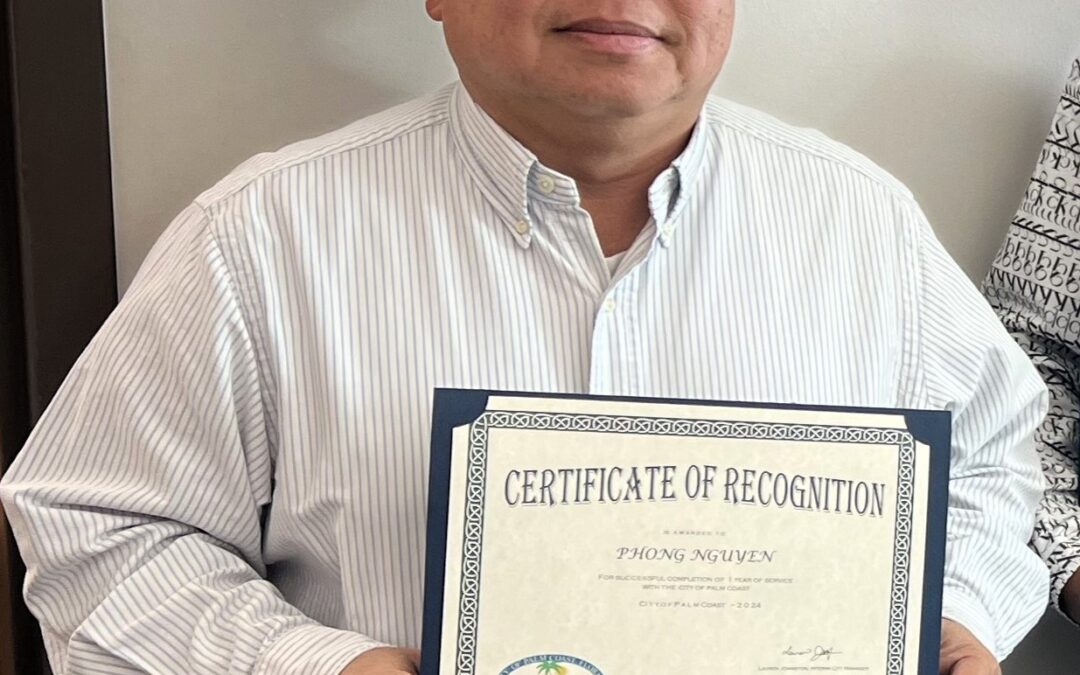 A person wearing a striped shirt holds a framed Certificate of Recognition