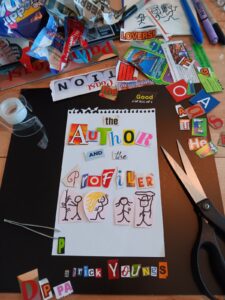 A collage style artwork on a wooden surface featuring colorful cut out letters forming the words "The Author and the Profiler " Surrounding the paper are scissors, tape, paper clips, and assorted letter cut outs Hand drawn figures are also visible